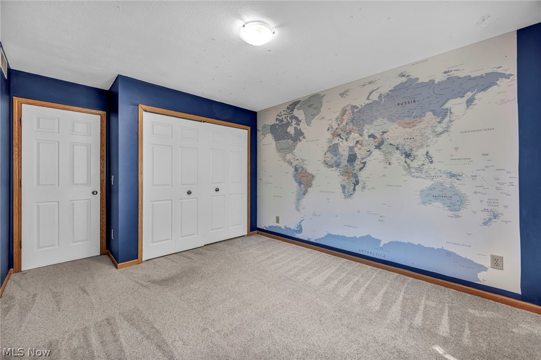 9842 Johnnycake Ridge Road Mentor, OH 44060 - Photo 16 of 40 Carpeted room featuring a large wall mural, white six-panel door, and bifold closet doors with wood trim