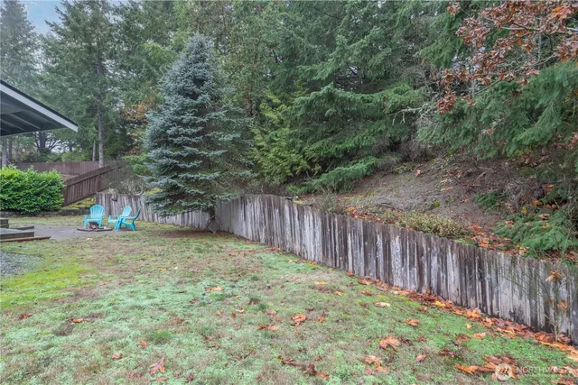 a view of a backyard with large trees and wooden fence