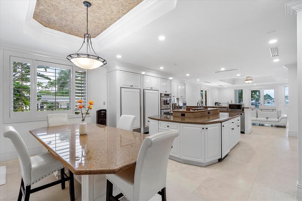 414 Riviera Isle Drive Fort Lauderdale, FL 33301 - Photo 26 of 70 a kitchen with stainless steel appliances granite countertop a dining table chairs and a chandelier