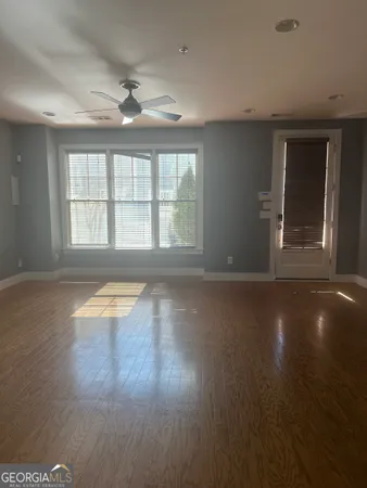 a view of empty room with wooden floor and fan