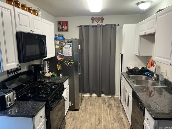 a kitchen with granite countertop a sink stove and refrigerator