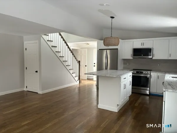 a kitchen with kitchen island granite countertop a stove top oven a sink and a wooden floor