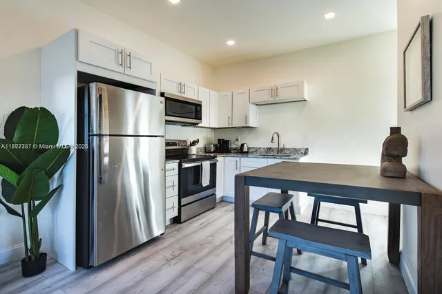 a kitchen with stainless steel appliances a refrigerator a sink a stove a dining table and chairs