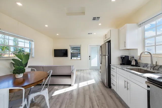 a living room with stainless steel appliances kitchen island granite countertop furniture a sink a rug and a window