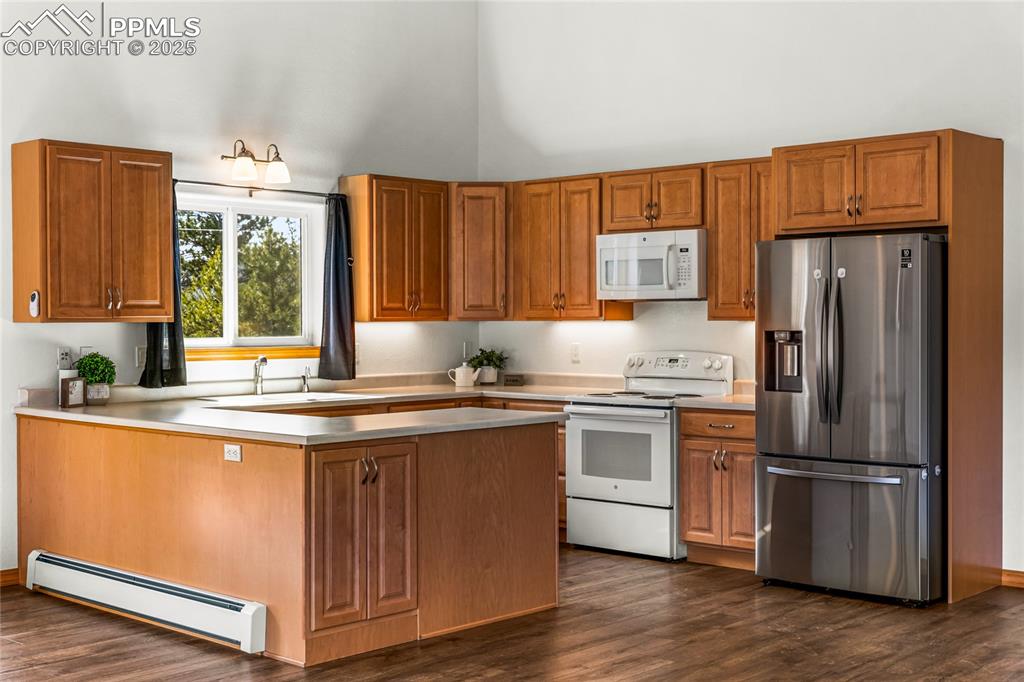 2649 Southpark Road Florissant, CO 80816 - Photo 9 of 42 a kitchen with stainless steel appliances granite countertop a refrigerator a sink dishwasher a stove and white countertops with wooden floor