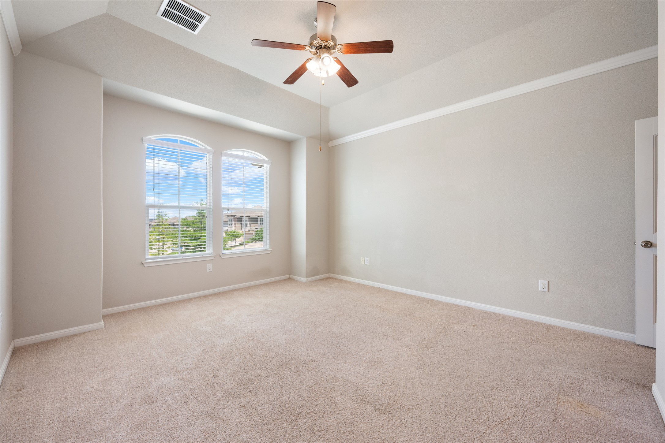 211 Parable Cove Pflugerville, TX 78660 - Photo 24 of 40 Spacious room featuring neutral carpet flooring, arched windows with blinds, a ceiling fan, crown molding, and vaulted ceilings