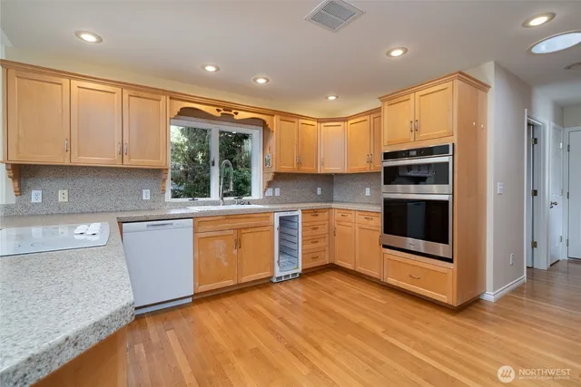 a kitchen with stainless steel appliances kitchen island granite countertop a stove a sink and white cabinets