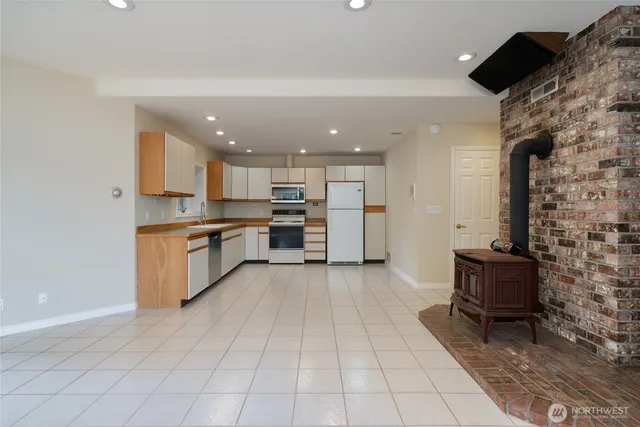 a view of an empty room with a window and kitchen view