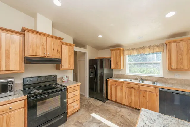 a kitchen with stainless steel appliances granite countertop a stove a sink and a refrigerator