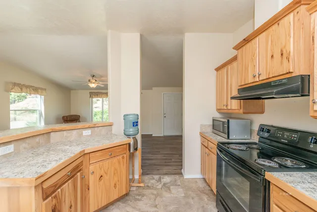 a kitchen with granite countertop a sink a stove and cabinets