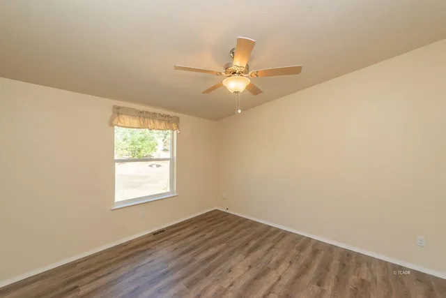 an empty room with a window and a fan