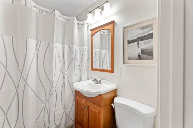 a bathroom with a granite countertop sink toilet and a mirror