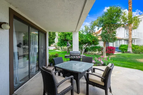 a view of a patio with a table chairs and a yard