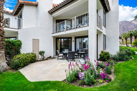 a front view of house and yard with beautiful flowers and seating
