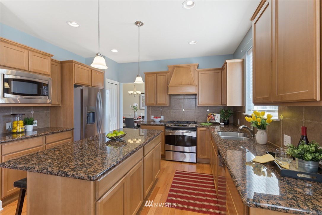 233 Chelan Avenue Northeast Renton, WA 98059 - Photo 8 of 16 a kitchen with stainless steel appliances granite countertop a sink a stove and a wooden floors
