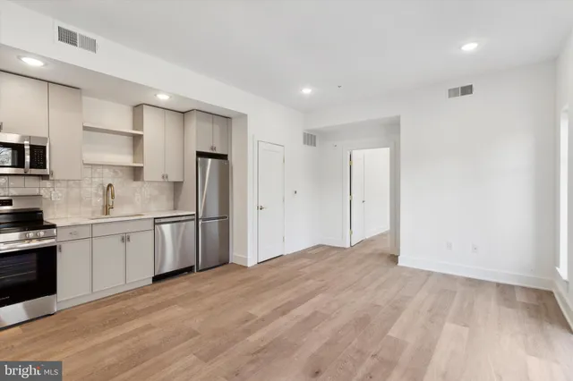 a kitchen with stainless steel appliances granite countertop a refrigerator sink and white cabinets