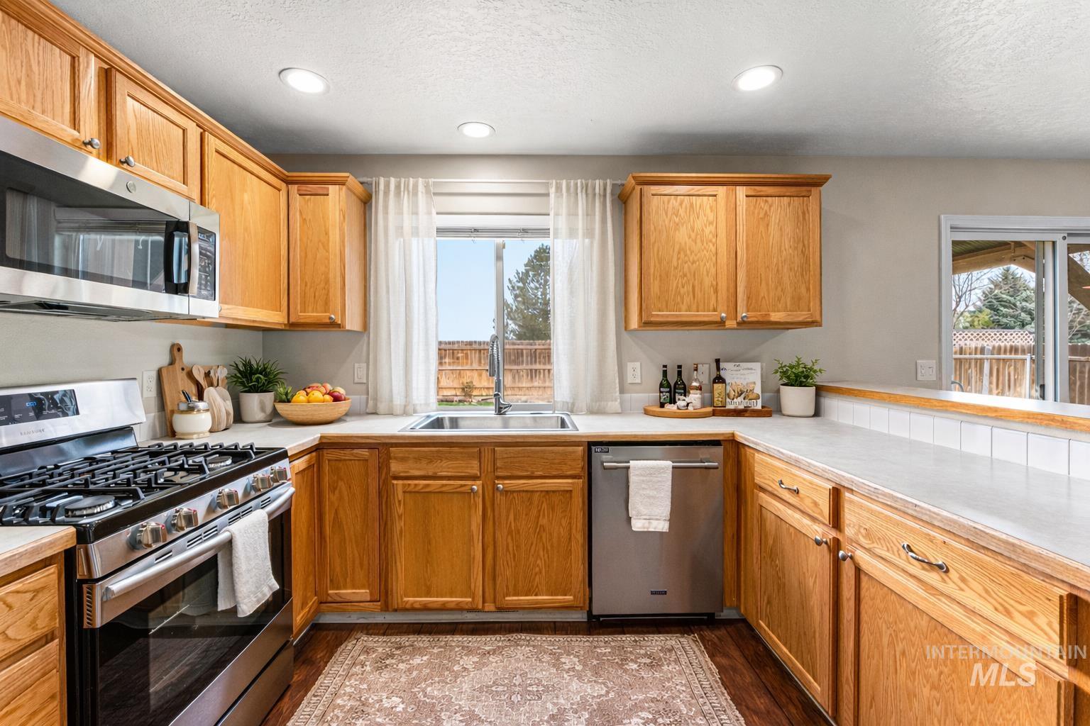 2503 Carnegie Street Caldwell, ID 83607 - Photo 6 of 20 Kitchen featuring stainless steel appliances, light countertops, recessed lighting, dark wood-style floors, and a textured ceiling