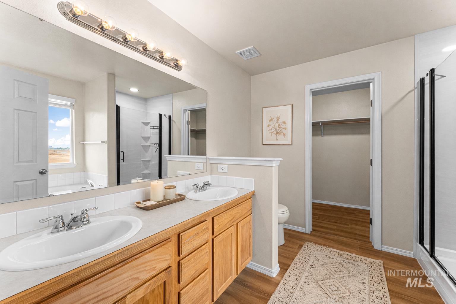 2503 Carnegie Street Caldwell, ID 83607 - Photo 10 of 20 Full bath featuring a spacious closet, a stall shower, a garden tub, double vanity, and light wood-style flooring