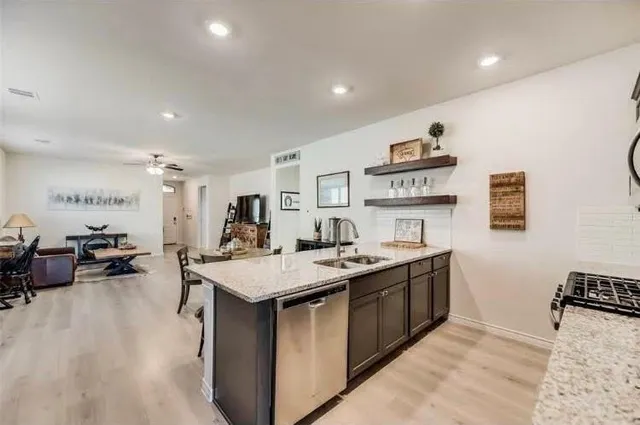 a open kitchen with stainless steel appliances granite countertop a sink a stove and a refrigerator
