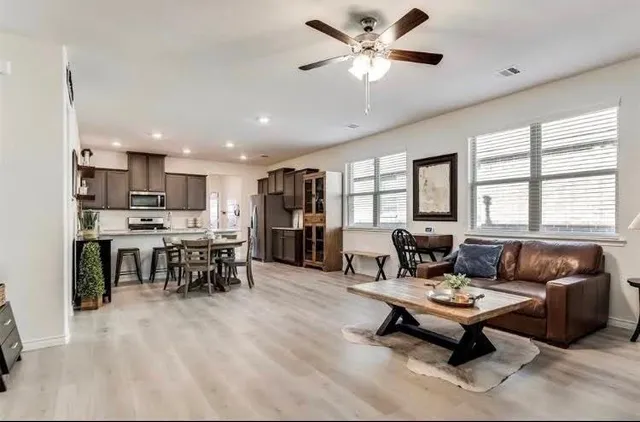 a living room with furniture kitchen view and a large window
