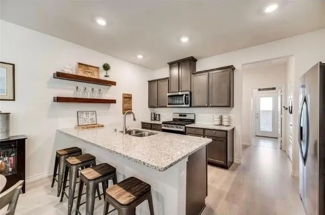 a kitchen with granite countertop a stove refrigerator and microwave