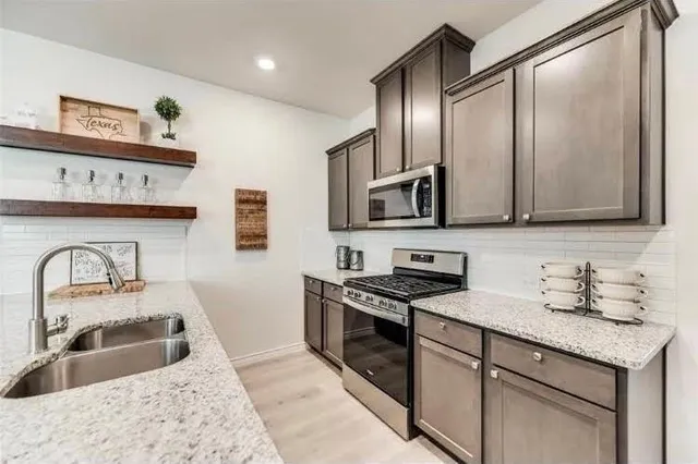 a kitchen with stainless steel appliances granite countertop a sink a stove and cabinets