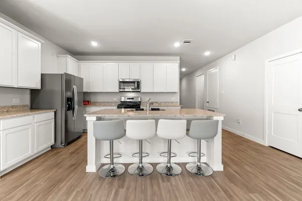 a kitchen with stainless steel appliances a dining table chairs microwave and refrigerator