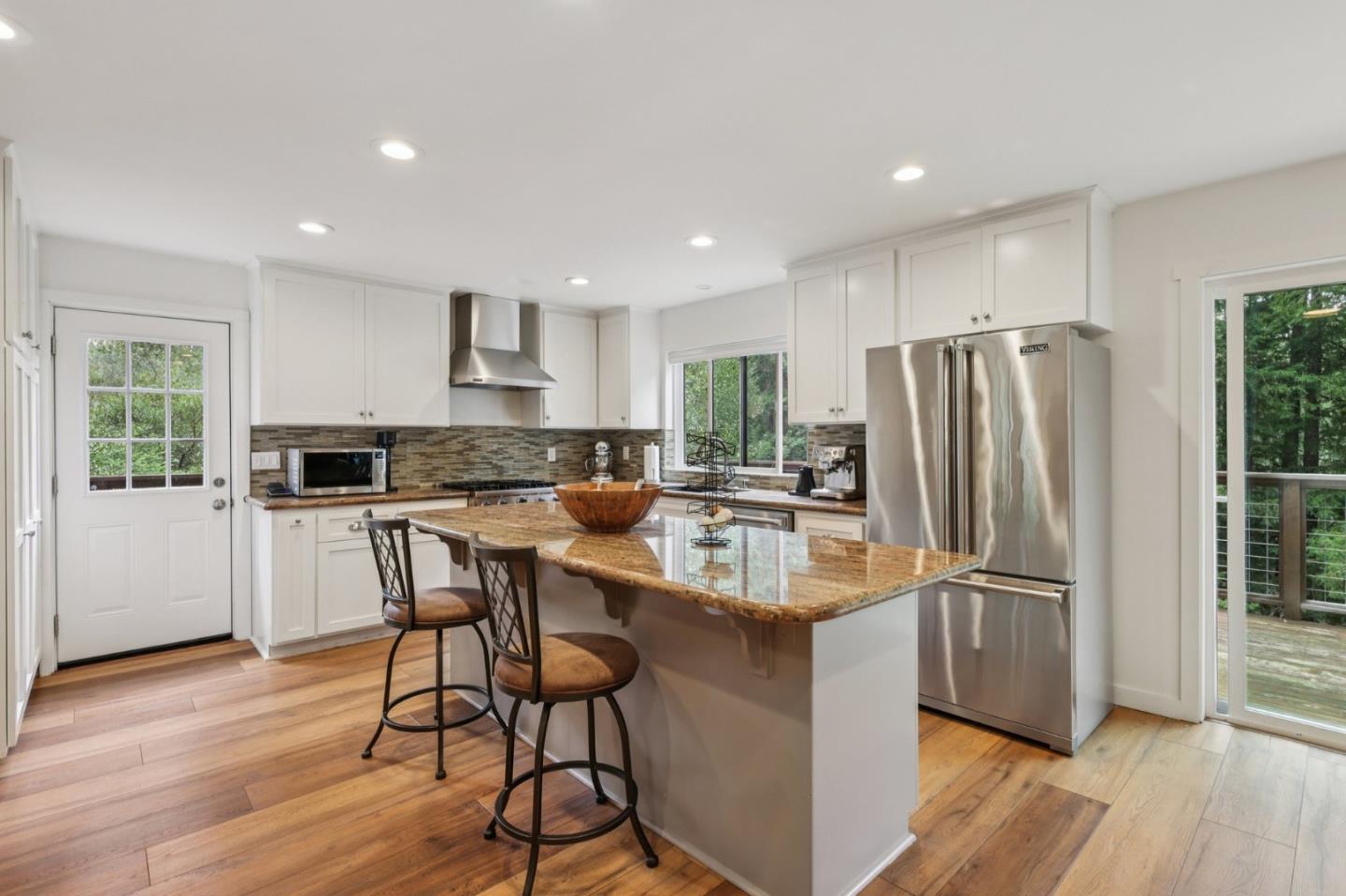 17386 Tressel Pass Road Boulder Creek, CA 95006 - Photo 10 of 41 a kitchen with stainless steel appliances granite countertop a refrigerator a stove a sink a dining table and chairs with wooden floor