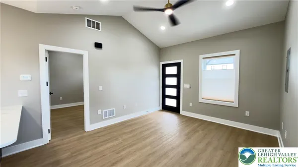 an empty room with wooden floor and windows