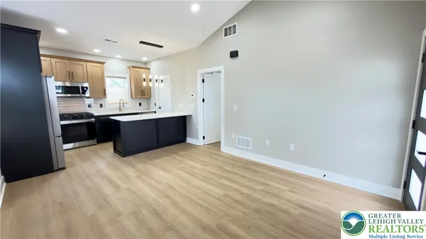 a large room with kitchen island a sink a stove and a refrigerator