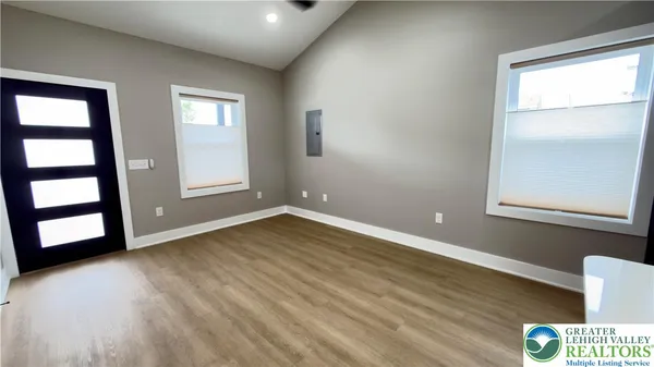 an empty room with wooden floor and windows