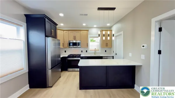 a large kitchen with stainless steel appliances kitchen island granite countertop a refrigerator and a sink