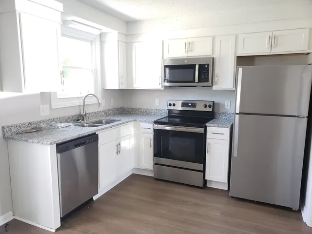 a kitchen with stainless steel appliances a white stove a microwave and a refrigerator
