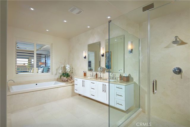a bathroom with a double vanity sink a large mirror a shower and bathtub