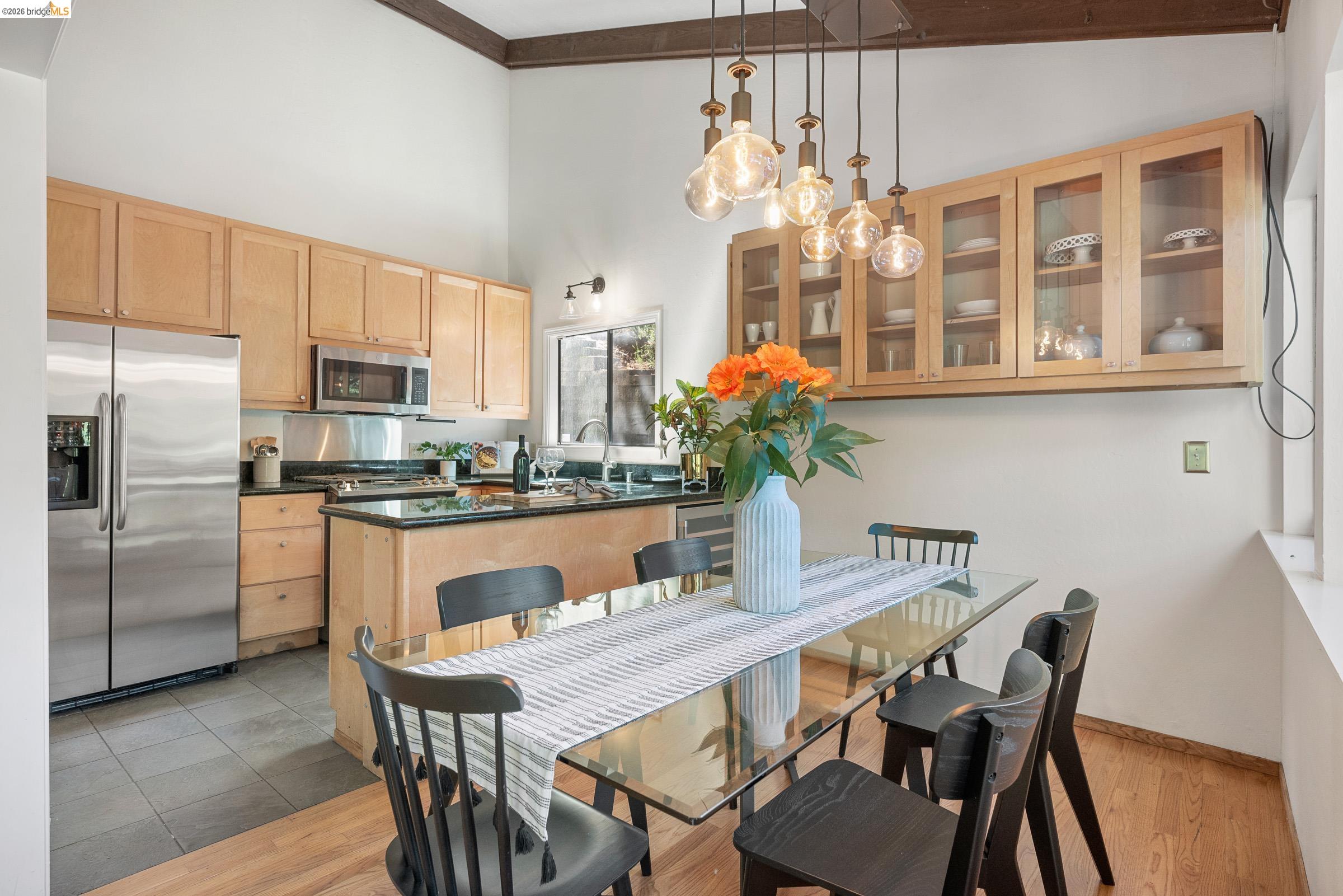 6600 Heather Ridge Way Oakland, CA 94611 - Photo 21 of 66 Open-concept kitchen and dining area featuring light wood cabinetry, stainless steel appliances, and a central island with a dark countertop