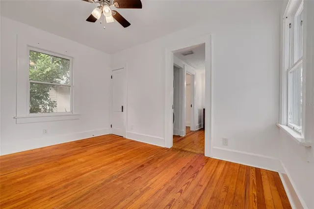 a view of empty room with wooden floor and fan