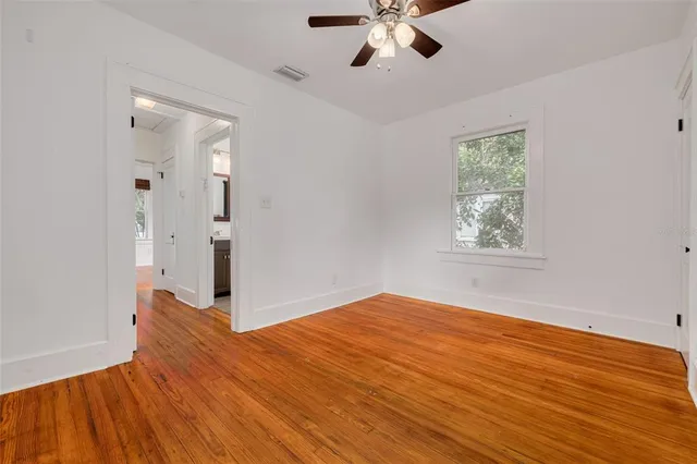 a view of an empty room with a window and wooden floor