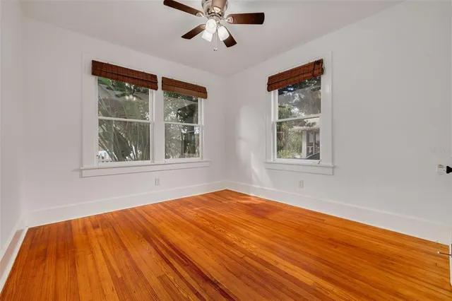 a view of empty room with wooden floor and fan