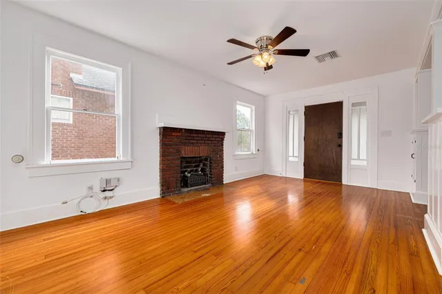 a view of empty room with wooden floor and fireplace