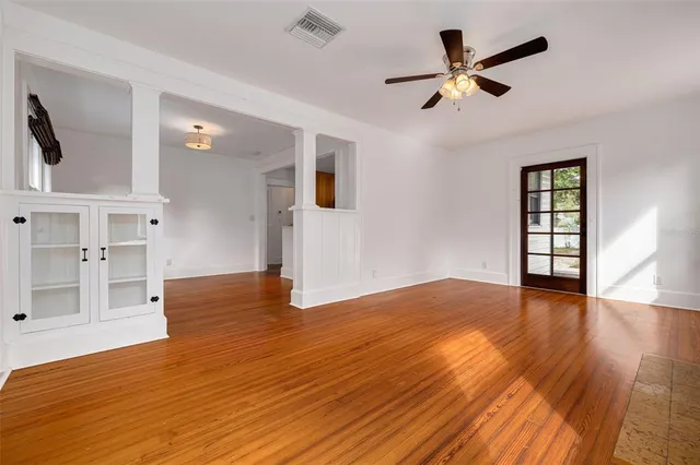 a view of empty room with wooden floor and fan