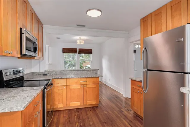 a kitchen with stainless steel appliances granite countertop a refrigerator a stove a sink and a wooden floors