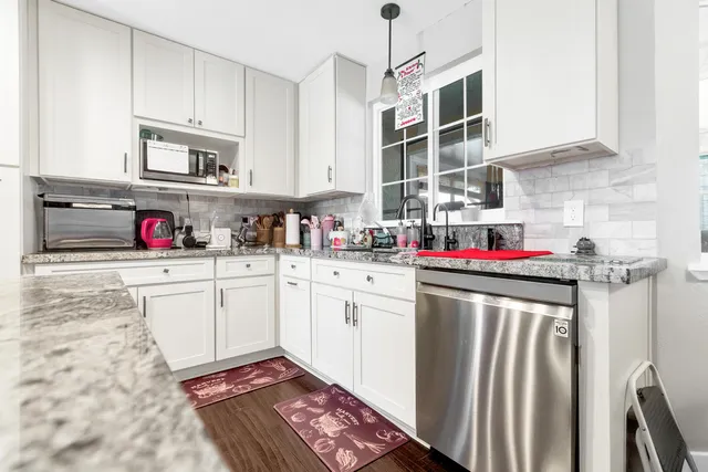 a kitchen with stainless steel appliances granite countertop a refrigerator and white cabinets
