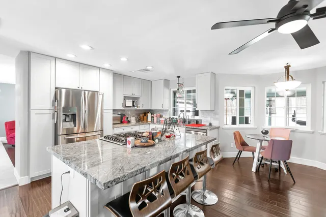 a kitchen with stainless steel appliances granite countertop a table chairs refrigerator and sink