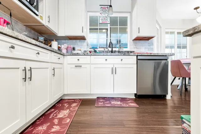 a kitchen with granite countertop a sink cabinets and stainless steel appliances