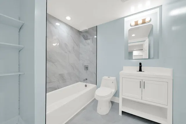 a bathroom with a toilet a sink a mirror and bathtub