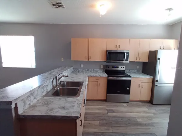 a kitchen with granite countertop a sink stainless steel appliances and cabinets