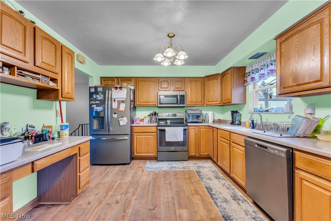 9642 Crow Road Litchfield, OH 44253 - Photo 21 of 50 Kitchen featuring light hardwood / wood-style floors, appliances with stainless steel finishes, a healthy amount of sunlight, and a notable chandelier