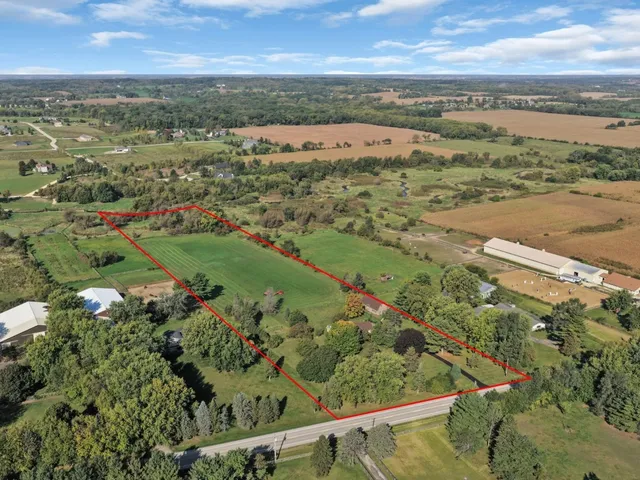 a view of a yard in front of a house with plants and large tree