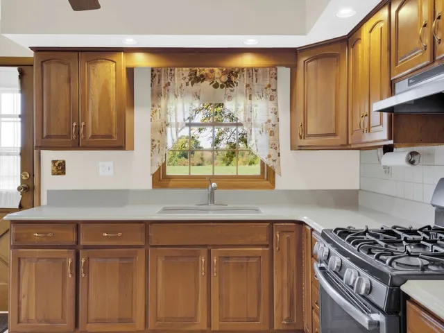 a kitchen with granite countertop wooden cabinets and a stove top oven