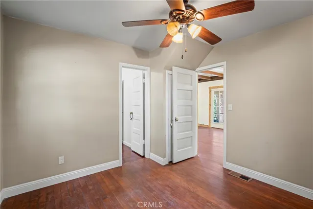 an empty room with wooden floor closet and fan